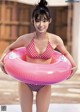 A woman in a red and white bikini holding a pink inflatable ring.