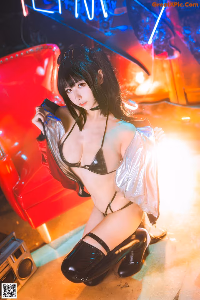 A woman in a black bikini posing in front of a neon sign.