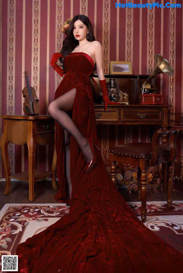 A woman in a red dress posing in front of a piano.