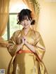 A woman in a yellow kimono standing in front of a window.