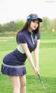 A woman in a blue uniform holding a golf club.