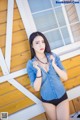 A woman in a denim shirt and black panties posing for a picture.