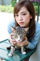 A woman holding a cat on a green table.