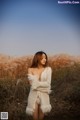 A woman in a white sweater standing in a field.