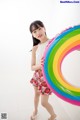 A young girl holding a rainbow shaped pool float.