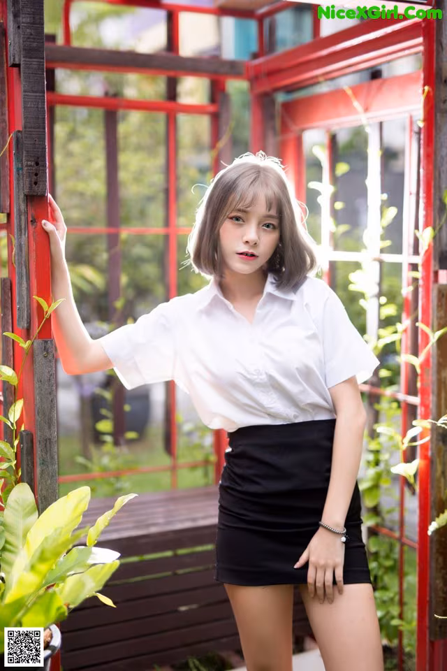 A woman in a white shirt and black skirt posing for a picture.