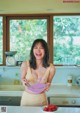 A woman holding a bowl of strawberries in a kitchen.