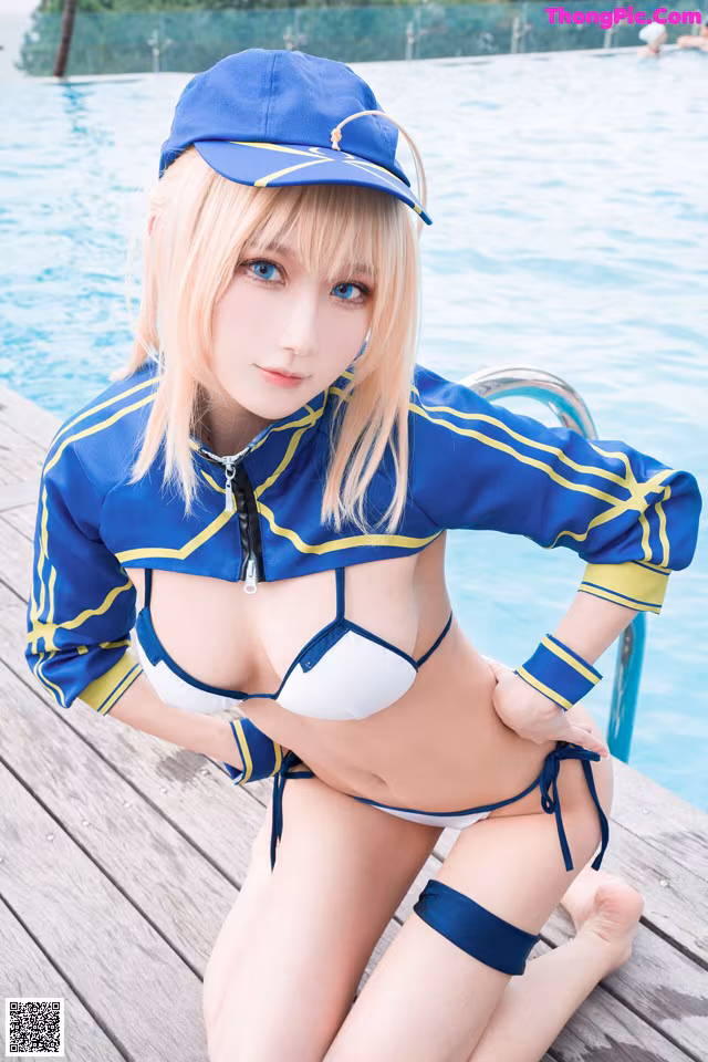 A woman in a blue and white bikini sitting on a dock.