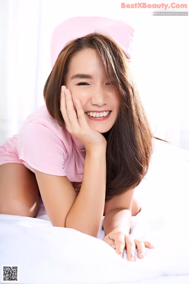 A woman laying on a bed wearing a pink hat.