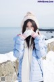 A woman in a blue jacket and white scarf standing in the snow.