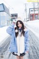 A woman in a blue jacket is standing in the snow.