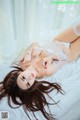 A woman laying on a bed in a white lingerie.