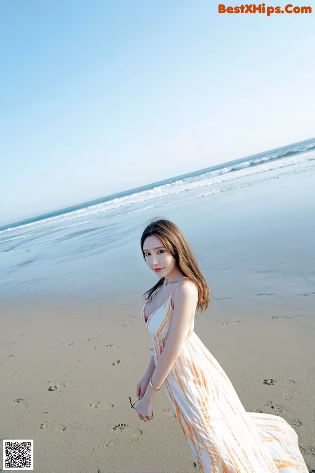 A woman in a long dress standing on a beach.