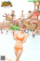 A woman in an orange bikini standing in a water park.