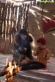 A woman and a child sitting next to a fire.